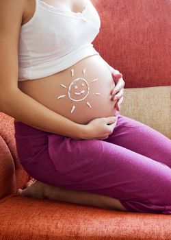 Pregnant woman belly with drawn sun by creme