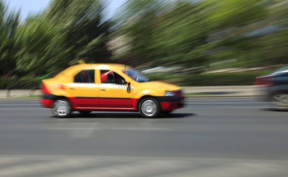 Motion blurred image of a taxi in motion.The image presents a combination of panning and zomming blurred movements at the shooting moment.