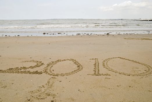 The year 2010 written in the sand on an coast beach.