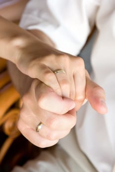 man's hand holds the woman's hand. Wedding rings on their fingers