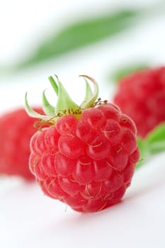 Raspberries with green leaves on white background