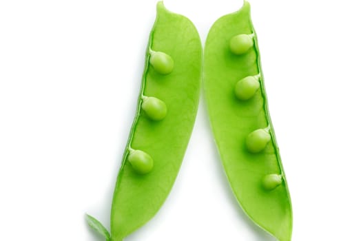  A close-up of a pea pod split open revealing peas on white background
