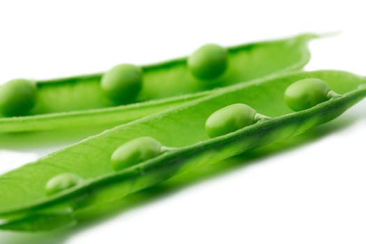  A close-up of a pea pod split open revealing peas on white background
