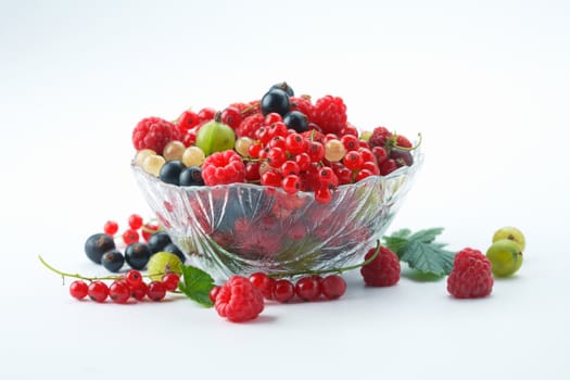 Mixed summer splitted berries in a cristal bowl on white