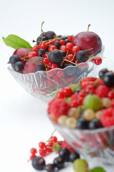 Mixed summer splitted berries in a cristal bowl on white