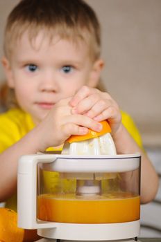 The child in a yellow vest to wring out juice  from an orange