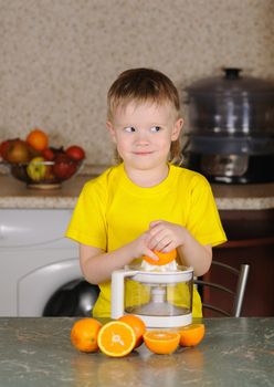 The child in a yellow vest to wring out juice  from an orange