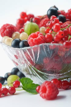 Mixed summer splitted berries in a cristal bowl on white