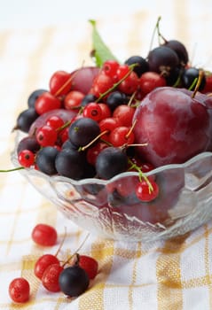 Mixed summer splitted berries in a cristal bowl on white