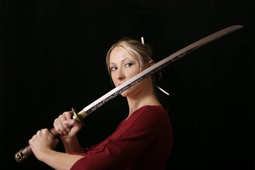 Young female grips a samurai sword, eyes fixed on opponent.