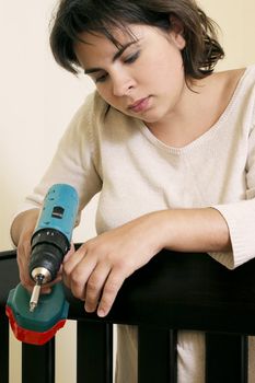 Tired young mother putting together baby's cot