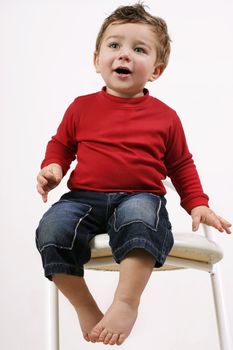 Adorable young toddler sitting on a white stool 
