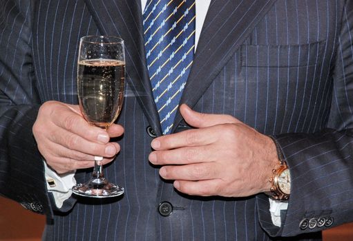 Business toast. A man holds in his hand, wine glass with champagne.