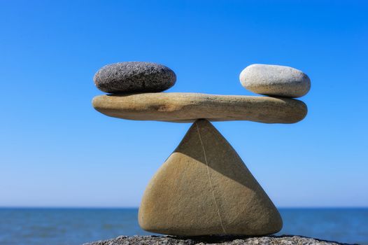 Symbol of scales is made of pebble on the cliff