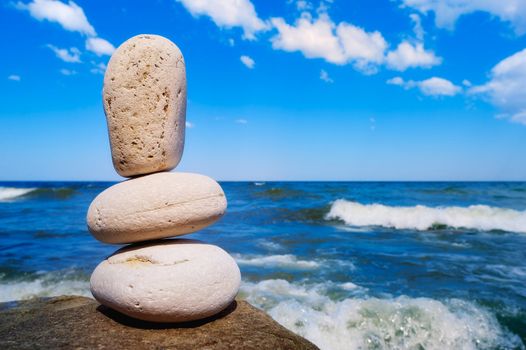 Three white pebbles against the background of the sea and sky
