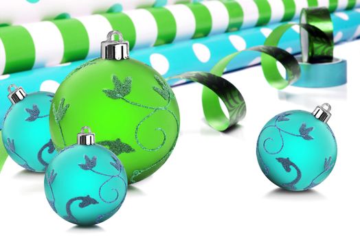 Rolls of gift wrapping paper and ribbon with blue and green christmas baubles