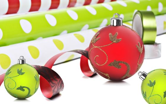 Rolls of gift wrapping paper and ribbon with red and green christmas baubles