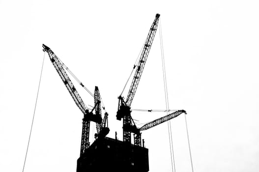 Black and white silhouette crane on top an under construction  building 