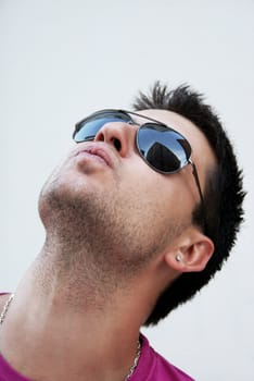 Young man with sunglasses looking into high-rise building which is reflected in his glasses.