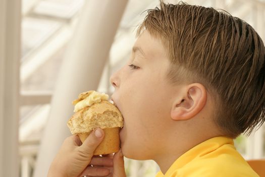 Child taking a bite of a muffin in cafeteria.