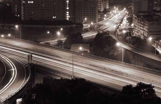 Traffic interchange night scene in modern city with cars light with dark buildings.