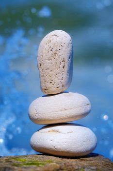 Three white pebbles against the background of the splashing sea water