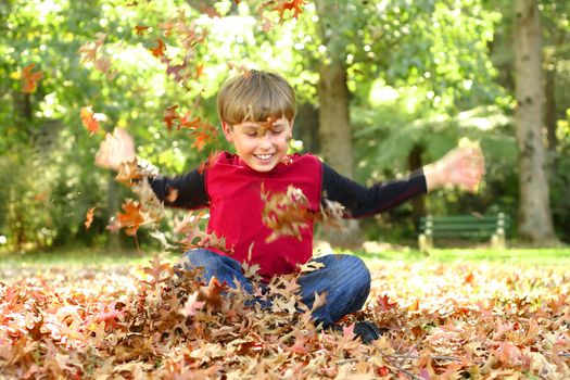 Child playing in leaves and laughing gregariously
Visible motion in arms and especially hands.