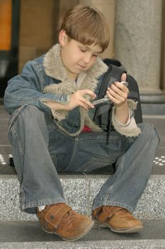 Schoolboy dialling a number on the cellphone or sending a text message sms.

400iso