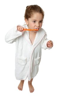A young girl holding an orange toothbrush and brushing her teeth.