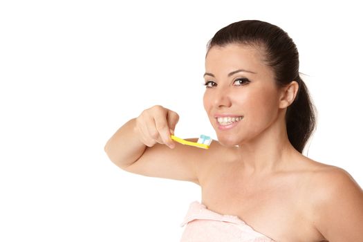 A female wrapped in a pink towel holding a toothbrush with toothpaste and smiling.