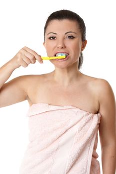 A woman uses a manual toothbrush and toothpaste to brush her teeth.