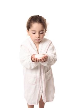 Little girl in white bathrobe holding a bar os soap in her hands.