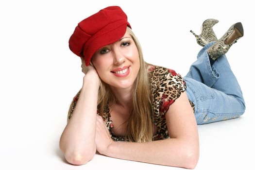 Casually dressed girl with red beret lying on stomach and smiling