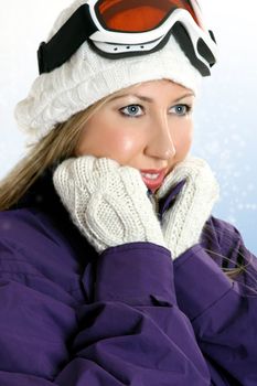 Woman dressed in winter attire, coat, gloves and warm woolen hat against a snowy backdrop