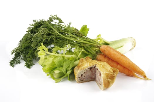 Contradiction between healthy food and junk food using a bunch of carrots and celery with a pork pie on a reflective white background 