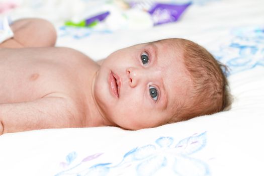 Curious baby girl lying on bed