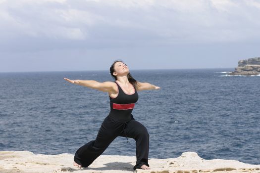 Beautiful woman stretching by the sea