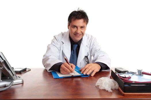 Medical doctor sitting at desk writing with pen on a  medical form.  He is looking up and smiling and listening.