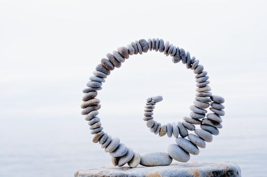 Spiral of pebbles on the top of boulder at the sea