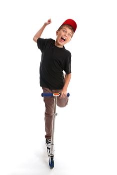 Headon view of a boy riding on and  playing with  a push scooter.  He has one hand in the air and an expression of enjoyment.