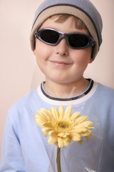 Boy holds a  gift of a creamy yellow gerbera.

