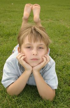child laying on stomach on lush green parklands. 