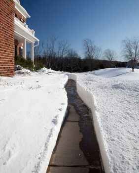 Pathway cut through deep snow towards the door of a modern single family home
