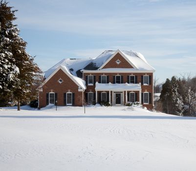 Modern home in a snowy setting with a conifer in the foreground