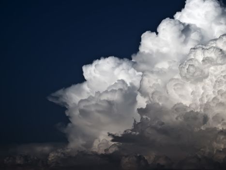 Towering detailed cumulus cloud over a dark blue sky