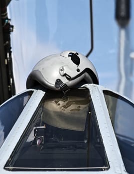 A fighter pilot's helmet lying on the cockpit canopy of his jet fighter