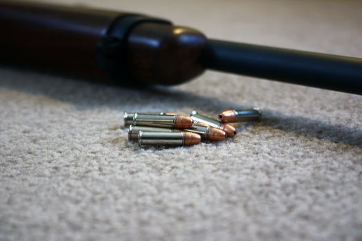 a small pile of bullets next to a rifle