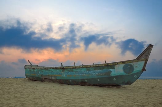 An abandoned boat at sunrise on a tropicla beach