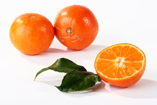 Half of a tangerine with leaves ������������� a tree, two tangerines on a back background.