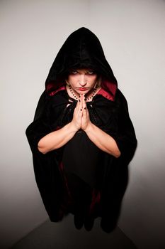 Witch in long black robe standing in corner